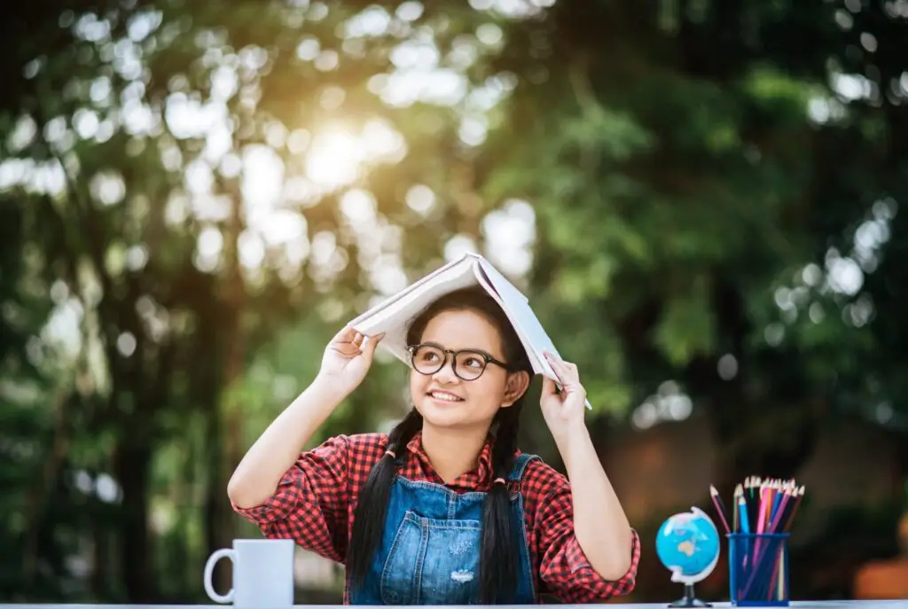 Student balancing a book on her head while studying outdoors