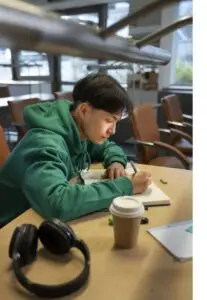 Secondary student writing notes at a desk